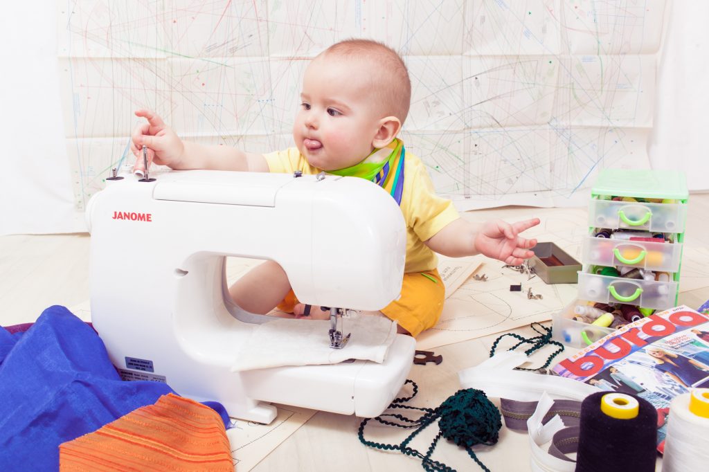baby learning to sew on a machine