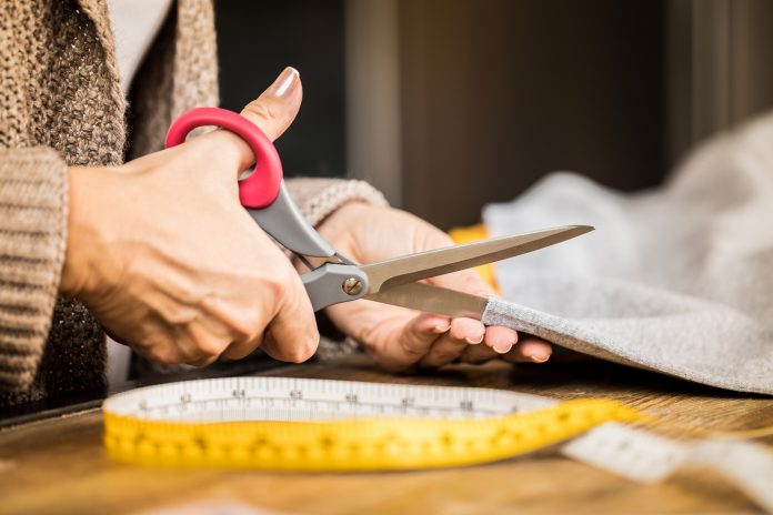 woman cutting fabric with scissors