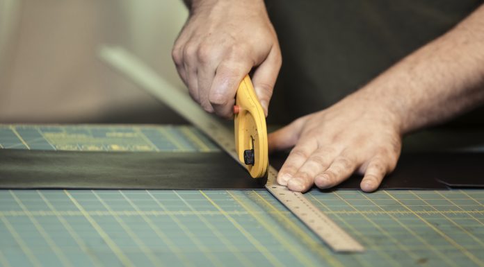 man using a rotary cutter on a piece of leather